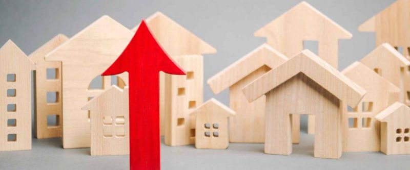  Flecha roja hacia arriba y casas de madera en miniatura. El concepto de aumento de los precios de la vivienda. 